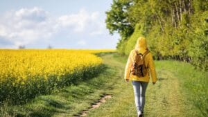 Дівчина гуляє весняною стежкою серед квітучого поля — ідея, куди поїхати відпочити навесні біля Києва для перезавантаження на природі.